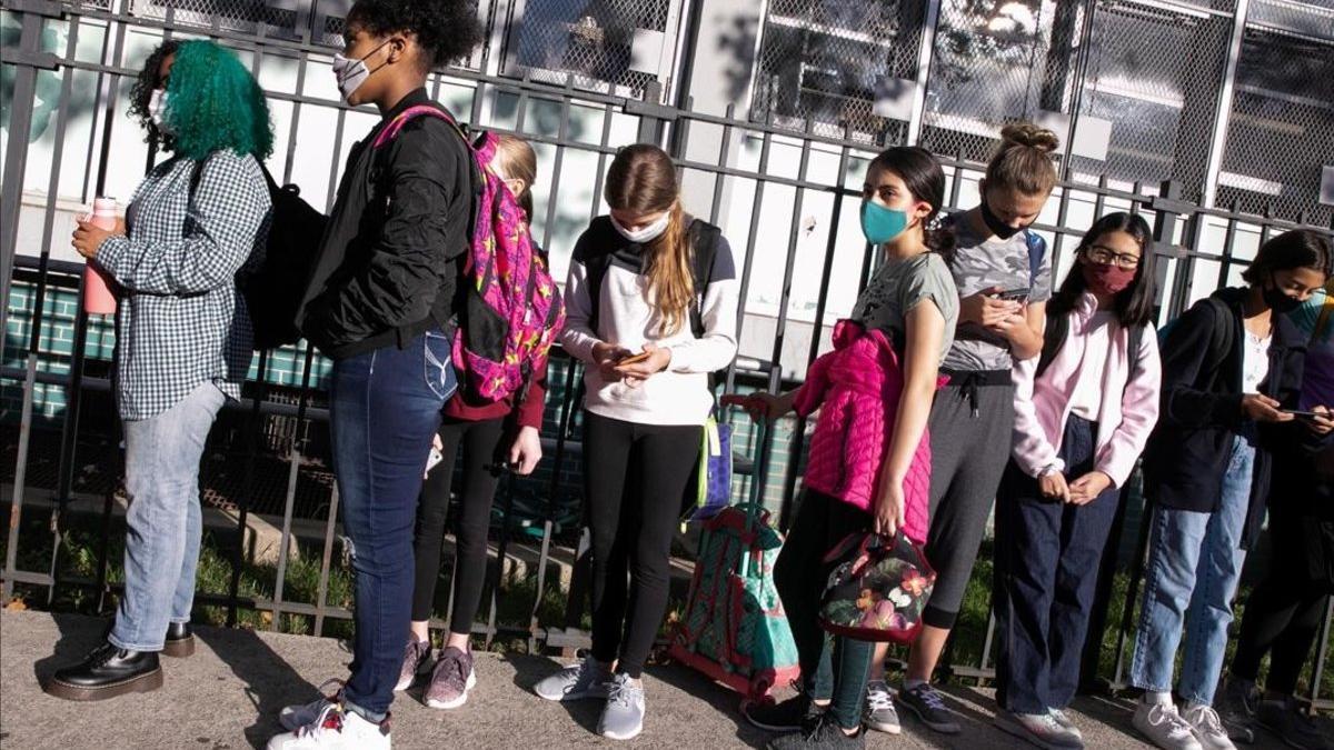 Los estudiantes de un colegio de Brooklyn esperan en fila para someterse a un control de temperatura el primer día de reapertura de la escuela.
