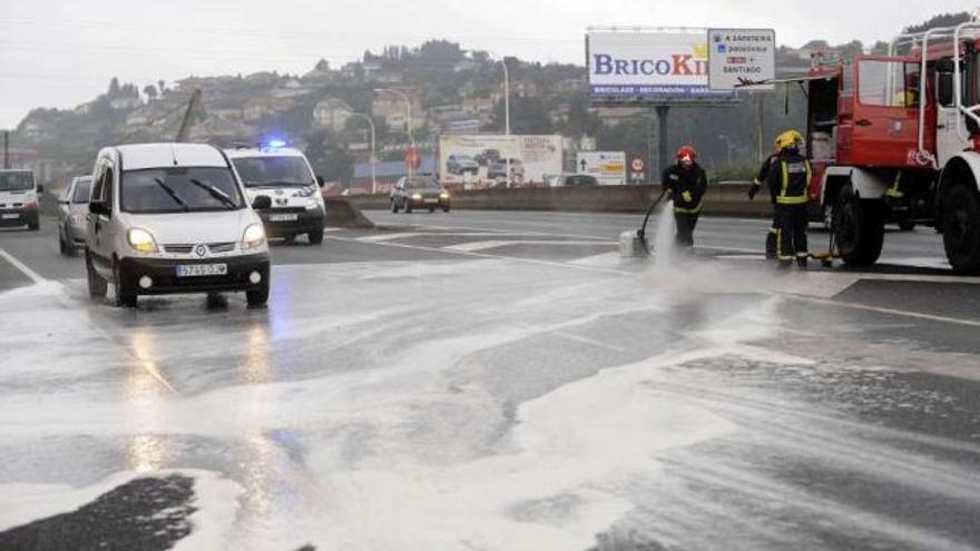 Los bomberos arrojan agua sobre la calzada de Alfonso Molina para diluir la mancha de aceite. / carlos pardellas