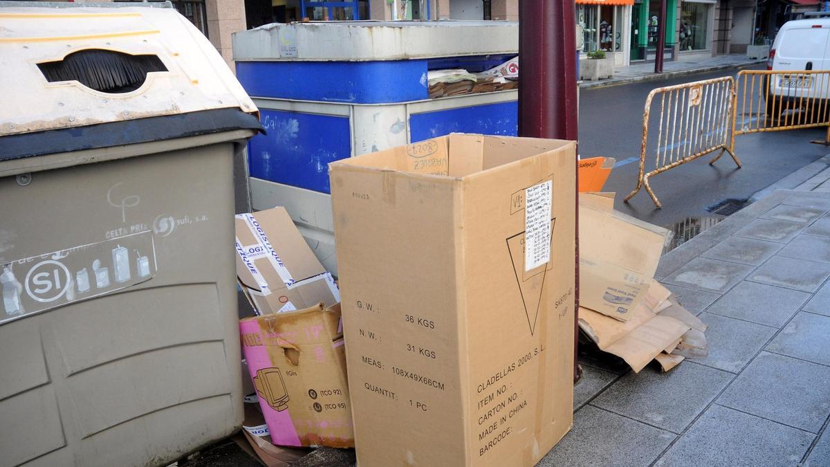Cajas de cartón de comercios depositadas frente a los contenedores.