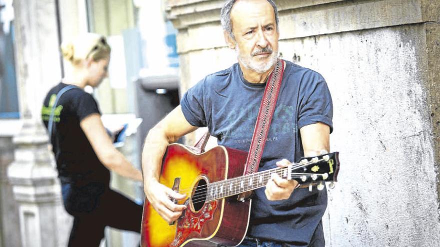 Still Morris posa con su guitarra ante un banco en Valencia.