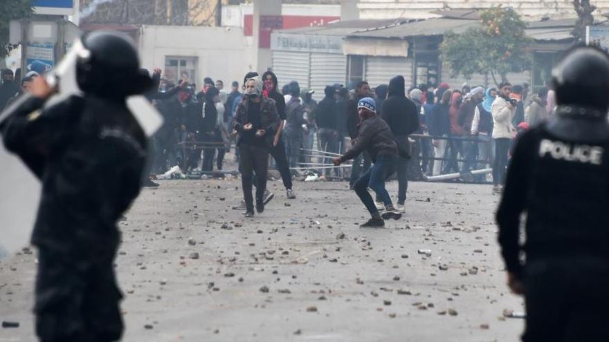 Protestantes cargan contra policías en Túnez.