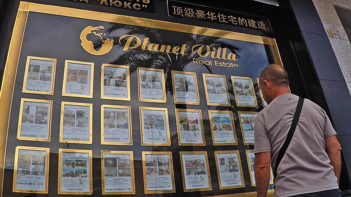 Un hombre mira el cartel de una inmobiliaria especializada en la venta a ciudadanos del Este.