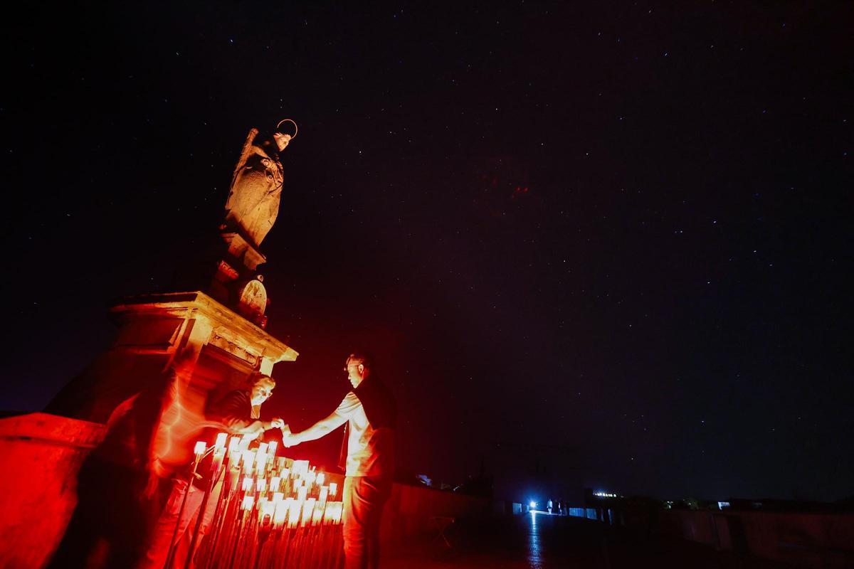 Un grupo de cordobeses enciende las velas del San Rafael del Puente Romano.