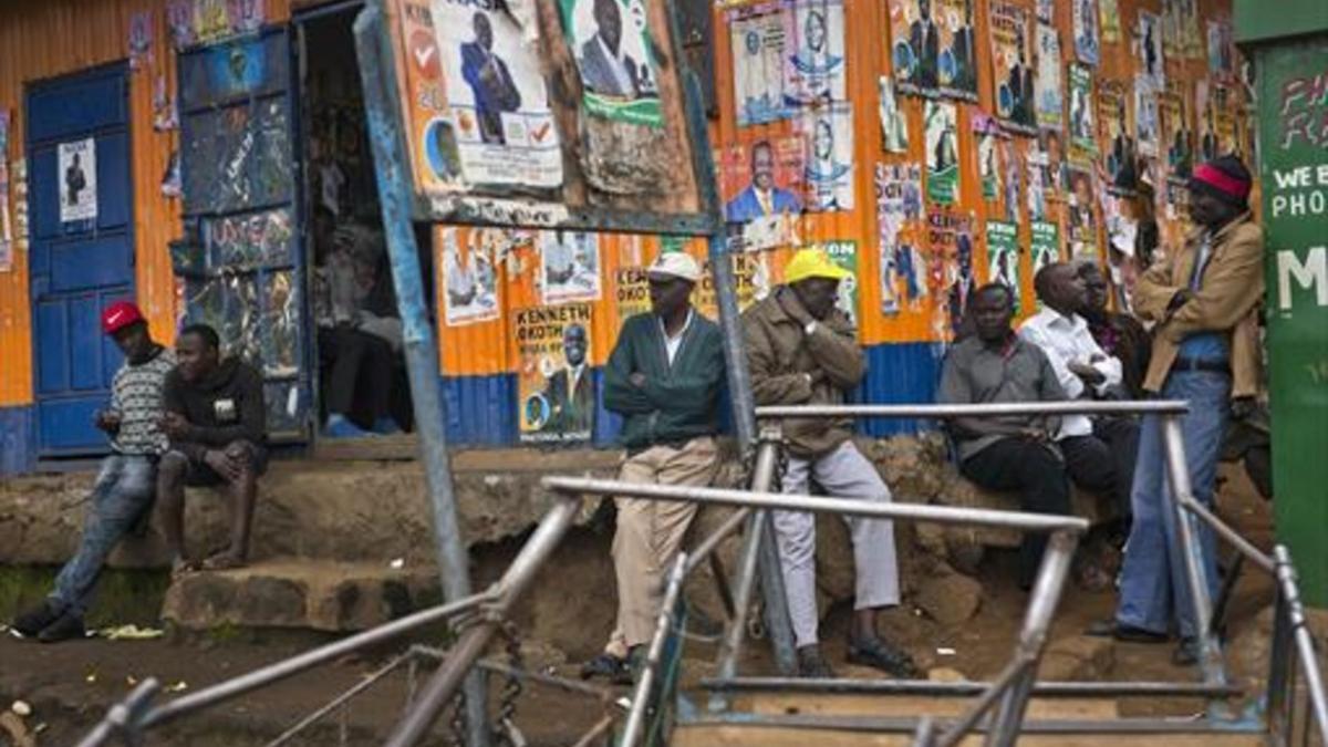 Candidatos Un grupo de kenianos, junto a un local con la fachada cubierta de carteles electorales, ayer, en una favela de Nairobi.