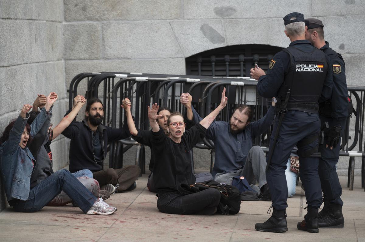 Efectivos de la Policía Nacional detienen a unos activistas de Rebelión Científica que lanzaron pintura roja en la Puerta de Los Leones del Congreso este jueves en Madrid. EFE/ J.J. Guillén