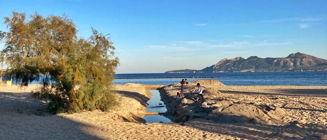 Varios niños juegan junto a una de las zanjas de la playa de Llenaire que, según los vecinos, podrían verter aguas fecales al mar.