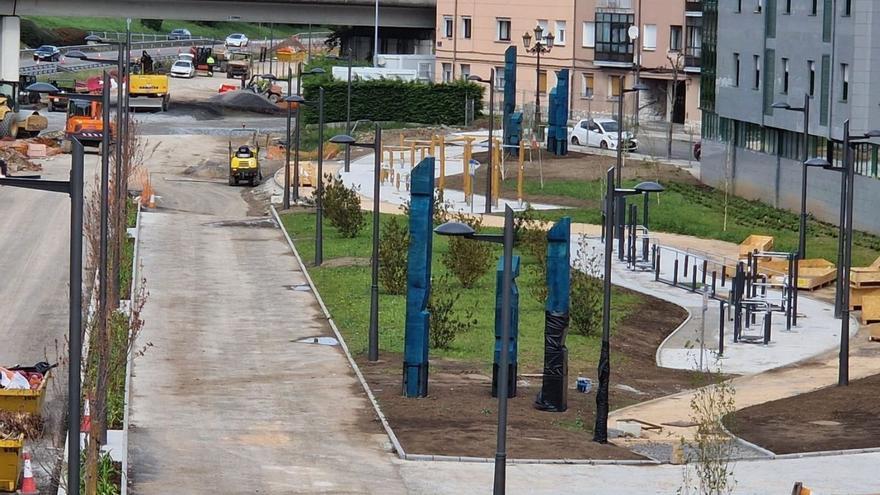 En primer término y al fondo, entre las farolas, los tótems colocados para decorar el parque lineal de Santullano.