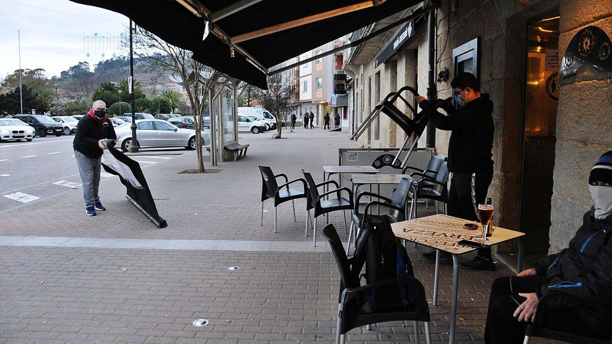 Hosteleros recogiendo la 
terraza de una cafetería de
 Cangas.   | // GONZALO NÚÑEZ