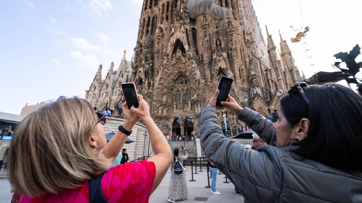 Dos turistas toman fotos de la Sagrada Família, este lunes