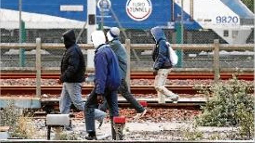 Migrants fent camí per les vies del tren per accedir a l&#039;eurotúnel.