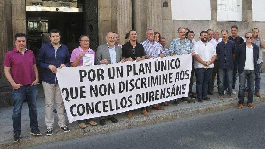 Alcaldes y diputados sujetando la pancarta de protesta en la puerta del Pazo Provincial, ayer. // Iñaki Osorio