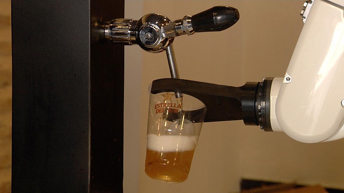 Un brazo robótico sirve cervezas a los clientes de un bar en Sevilla