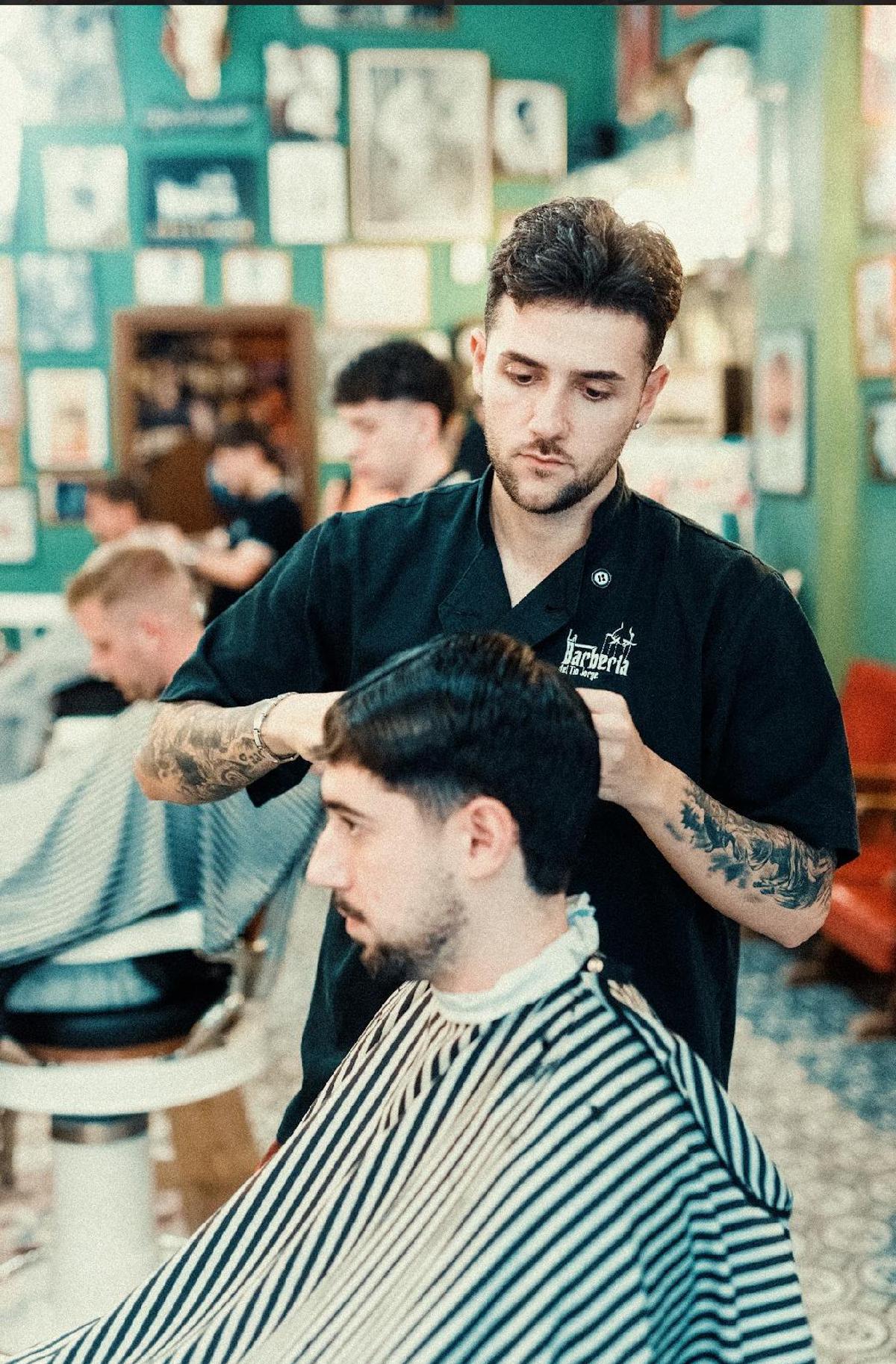 Un peluquero cortándole el pelo a uno de sus clientes