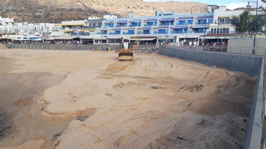 Una tractor reparte la arena a lo largo de Playa de Mogán.