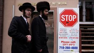 Dos hombres pasan ante un cartel informativo sobre el brote de sarampión en Brooklyn, Nueva York. 