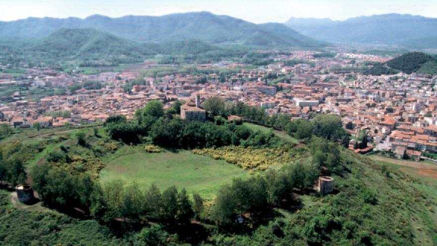 Imatge aèria del volcà Montsacopa amb l’entramat dels carrers de la ciutat d’Olot als seus peus