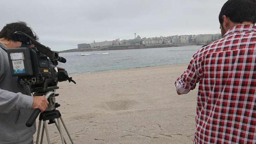 Dos cámaras enfocan los hoyos realizados por los jóvenes estudiantes en la playa de Riazor. / 13fotos