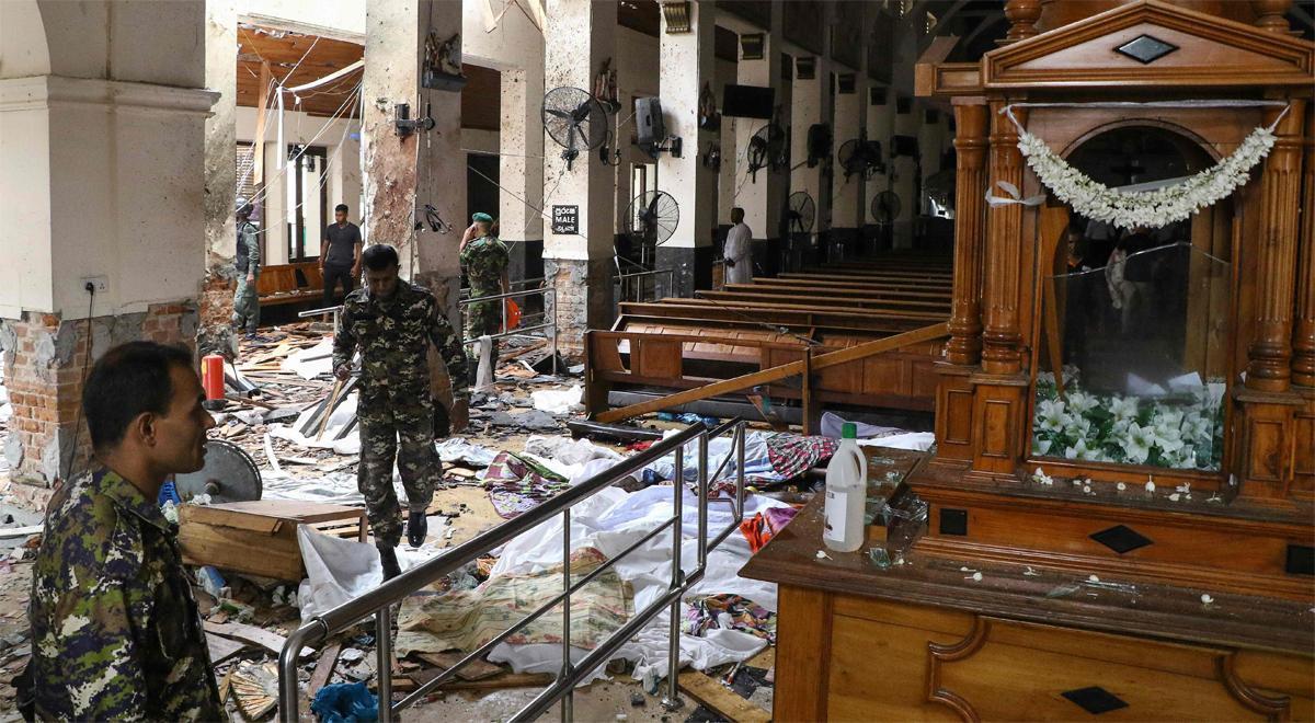 Personal de seguridad de Sri Lanka camina junto cadáveres cubiertos con escombros  en el Santuario de San Antonio después de una explosión en la iglesia de Kochchikade.