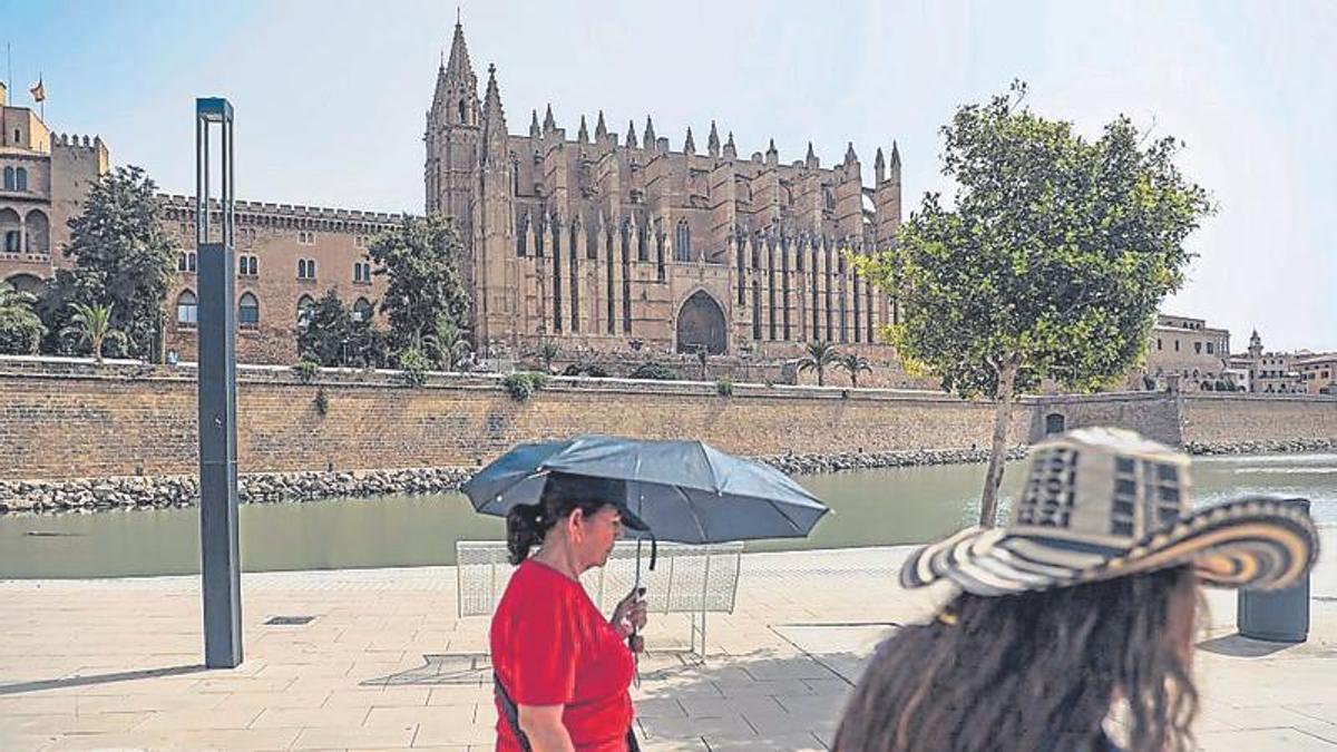 Turistas caminando bajo un sol de justicia en el Parc de la Mar.