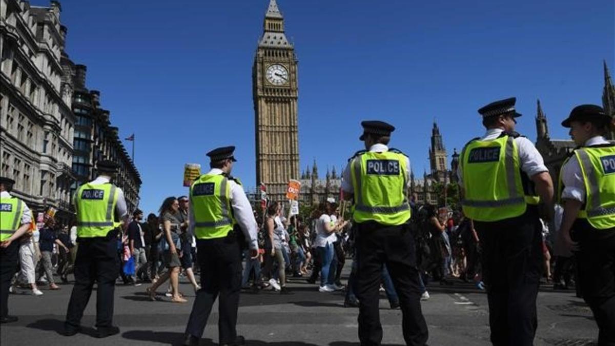 La policía londinense controla a los manifestantes anticonservadores en una marcha en la plaza del Parlamento, en el centro de Londres.
