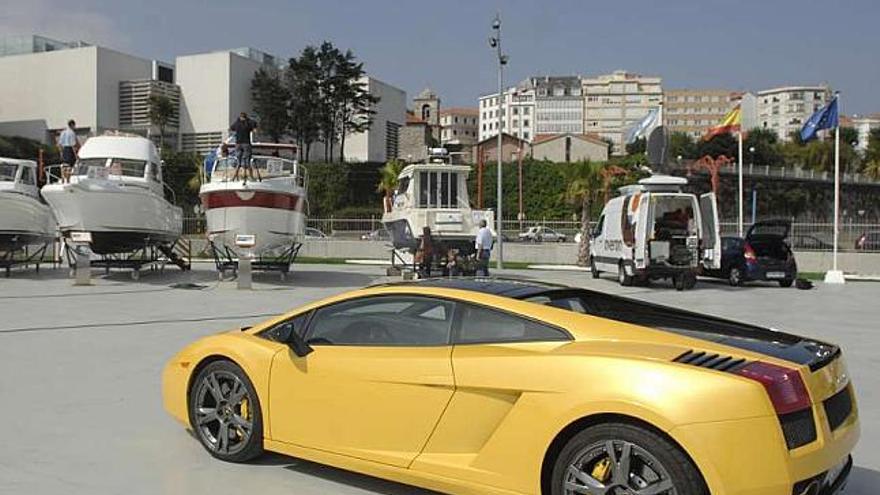 En primer plano, el coche deportivo de marca Lamborghini; al fondo, varios veleros a la venta. / thays r. paz