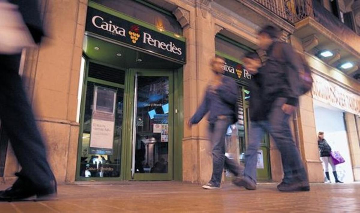Diversos ciutadans passen davant una oficina de Caixa Penedès del carrer de Pelai de Barcelona, ahir. Diversos ciutadans passen davant una oficina de Caixa Penedès del carrer de Pelai de Barcelona, ahir.