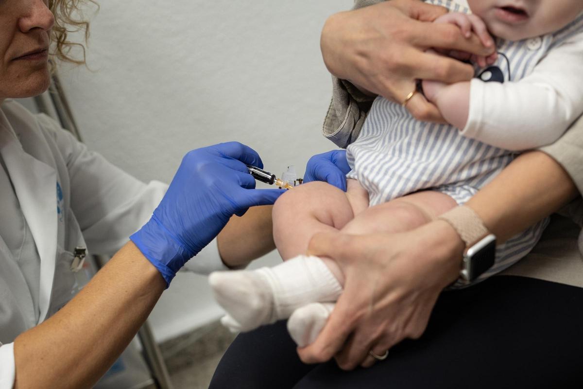 Una enfermera pone una vacuna a un bebé.