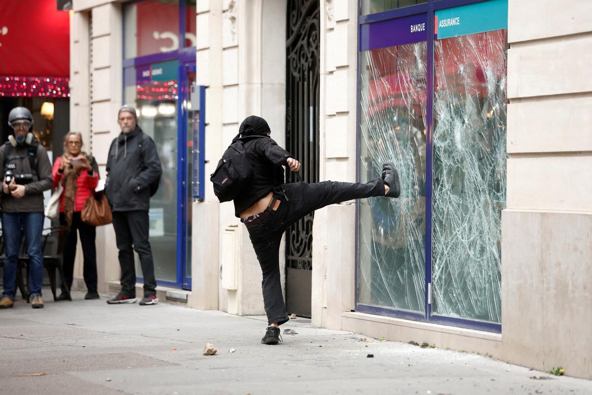 Un manifestante destruye la ventana de un banco durante los enfrentamientos en una manifestación en París como parte de un día nacional de huelga y protestas por salarios más altos.