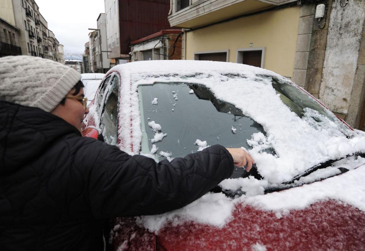 Una vecina retira nieve del parabrisas, en su coche en Lalín. |   // BERNABÉ/JAVIER LALÍN