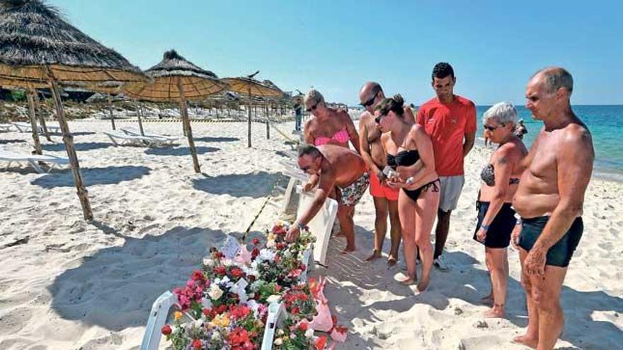 Turistas dejan flores en el lugar del atentado del viernes, una playa ayer casi vacía.