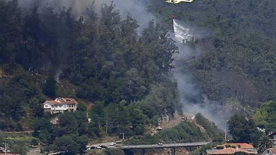 Un helicóptero libera agua sobre la zona afectada. / JORGE SANTOMÉ