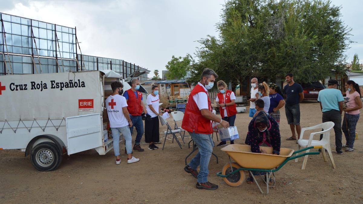 Trabajadores de Cruz Roja entregan comida a inmigrantes que viven en asentamientos en Córdoba.