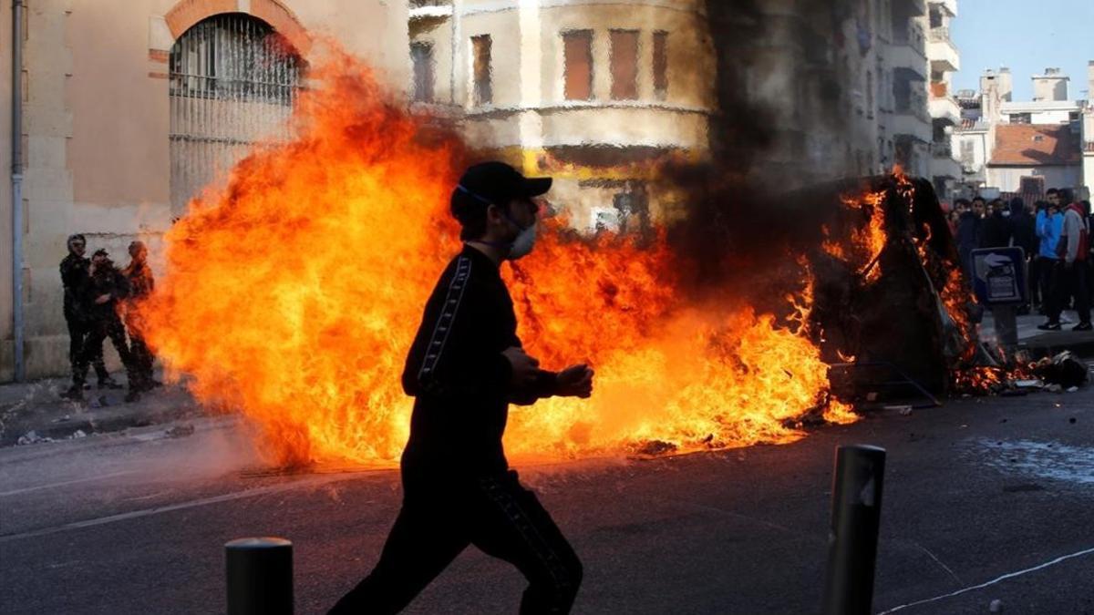 Unos jóvenes queman contenedores de basura en Marsella durante una manifestación contra los planes fiscales del Gobierno francés.