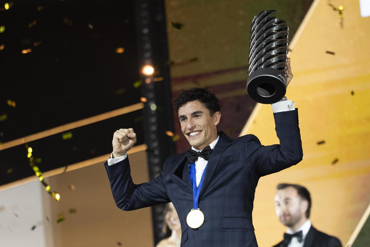 Marc Márquez levanta, con el brazo derecho, por si acaso, el trofeo de campeón del mundo de MotoGP.