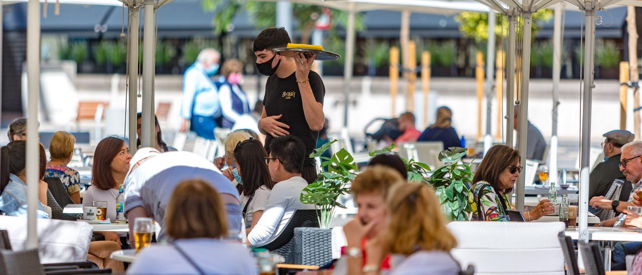 Un joven atiende la terraza de un bar.