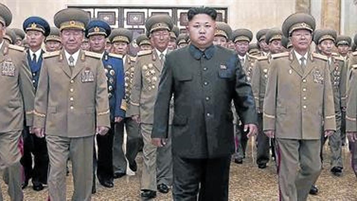 Kim Jong-un, al frente de su Ejército, en julio pasado. Abajo, un cartel antiamericano.