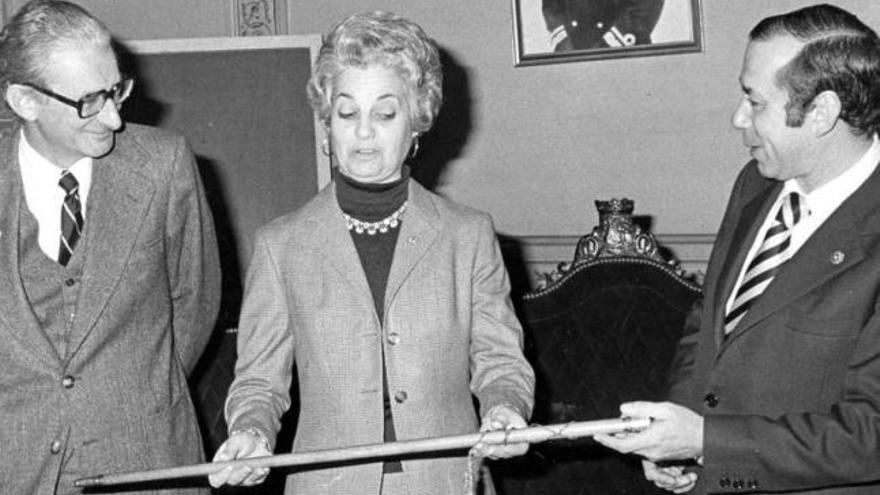 Emma G. Bermello recibe de García Picher el bastón de mando de Vigo (1978), junto al concejal José María Pernas. Abajo, Bermello, vestida de gallega de gala, en su toma de posesión en el Parlamento de Galicia (1981).  // Magar