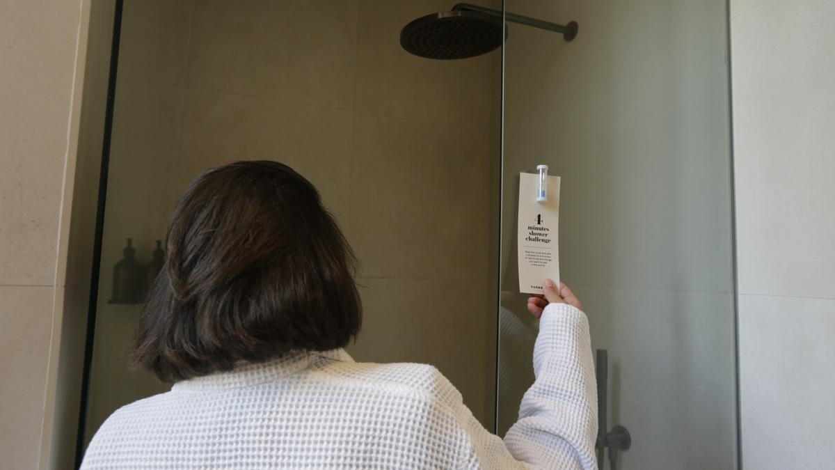 Una usuaria encuentra el reto y el reloj para reducir el tiempo de ducha y ahorrar agua, en el hotel Yurbban Passage.