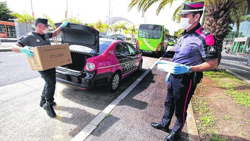 Efectivos de la Policía Canaria trasladan una caja con mascarillas hasta las instalaciones del Intercambiador de Santa Cruz de Tenerife.