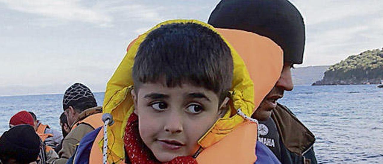 Un niño llega en una embarcación a la isla de Lesbos junto a otros refugiados