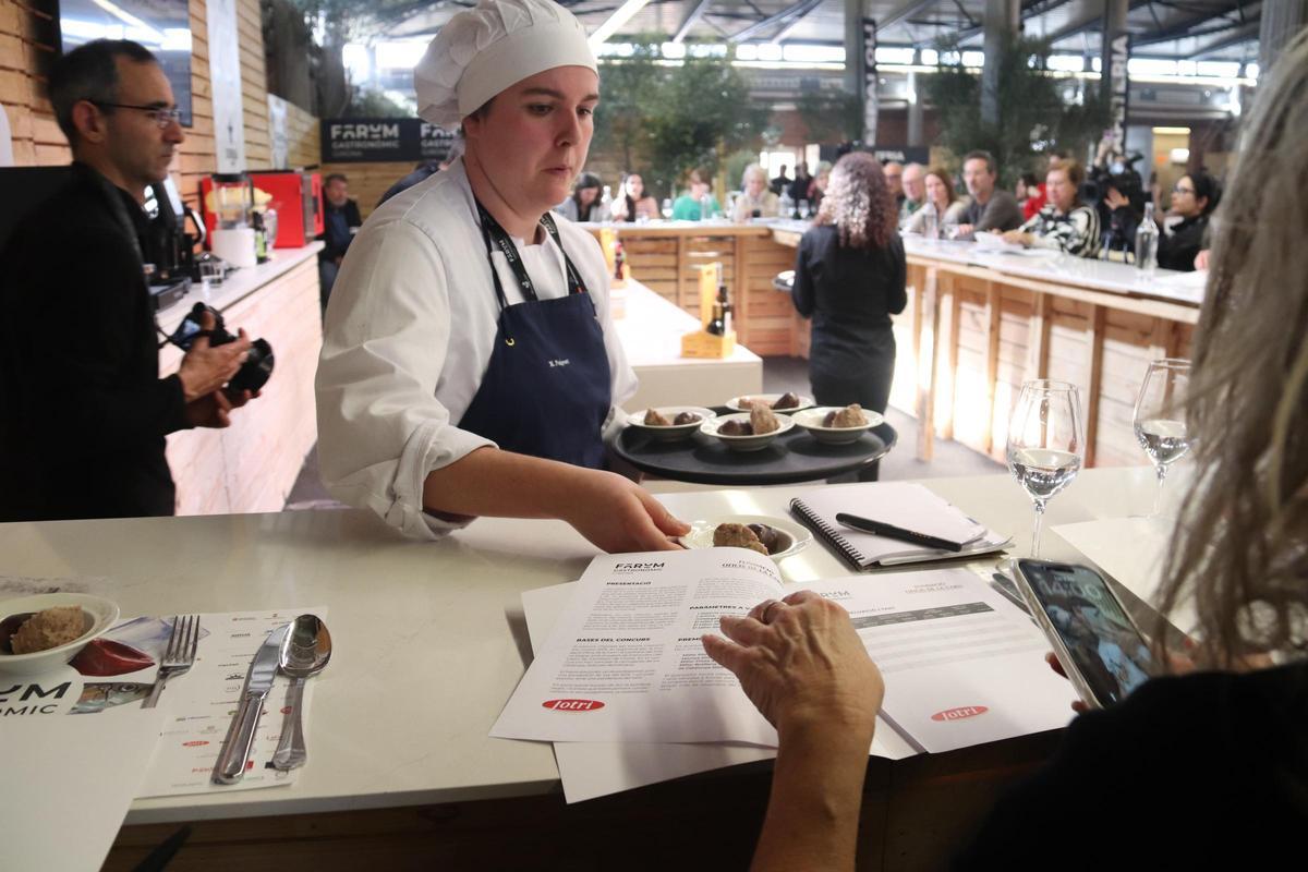 Una dona reparteix els plats amb mostres de pilota i carn d'olla en el concurs de Pilota i Botifarra Negra que s'ha fet al Fòrum Gastronòmic de Girona.