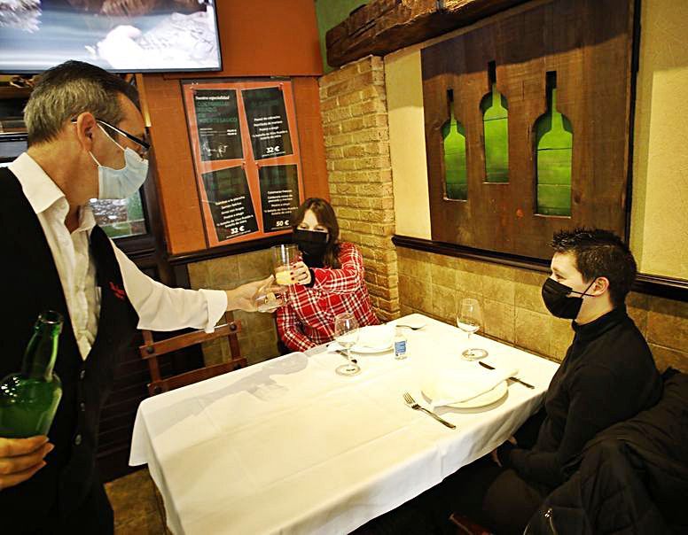 Un hostelero ofrece un culete de sidra a una clienta en la sidrería El Saúco, en Gijón.