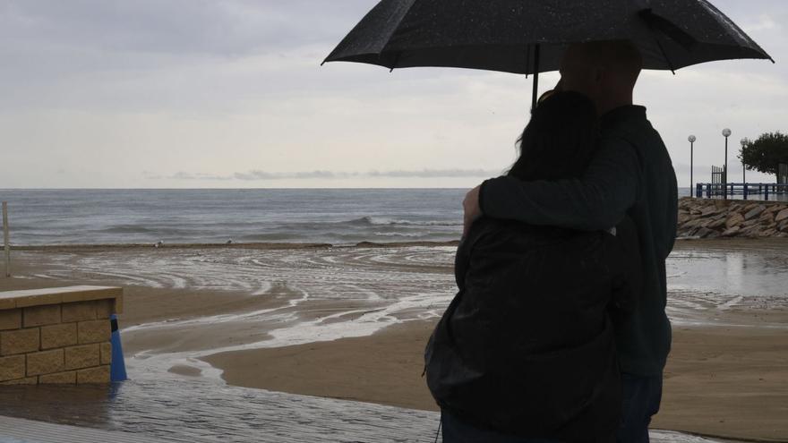 Una pareja se abraza bajo un paraguas frente a una playa de la provincia, en una imagen de archivo.