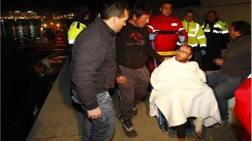 Compañeros del pescador herido lo arropan a su llegada al puerto de Alicante.