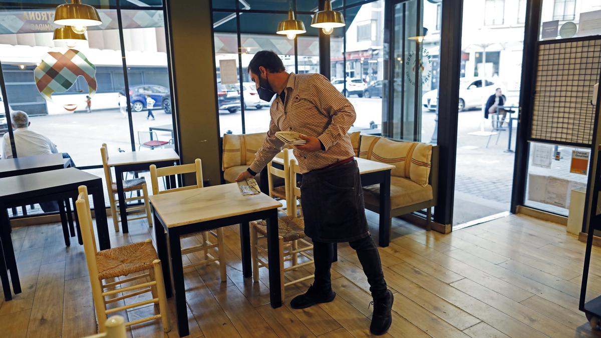 Un hostelero prepara el interior del local para un servicio de comidas con la ventilación de la puerta.