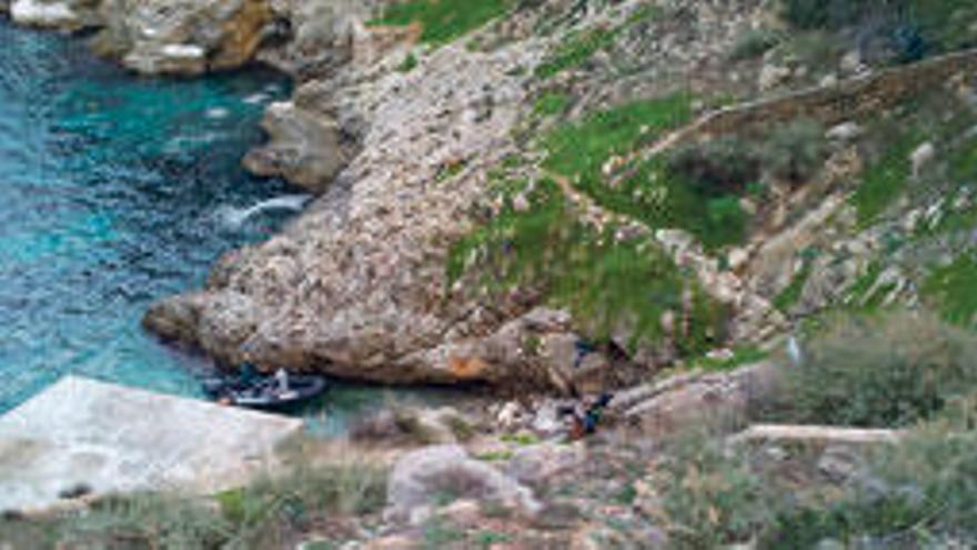 Agentes de la Guardia Civil, con una embarcación, junto a las rocas donde apareció el cadáver.