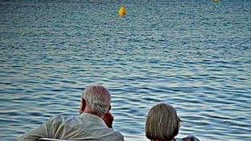 Una pareja de mayores sentados en una playa.