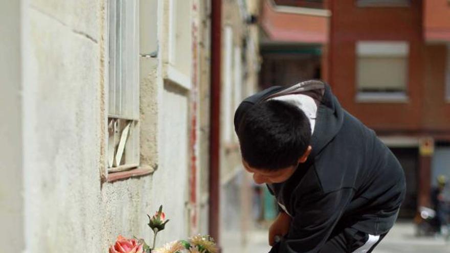 Un vecino coloca flores en homenaje a los dos niños asesinados.