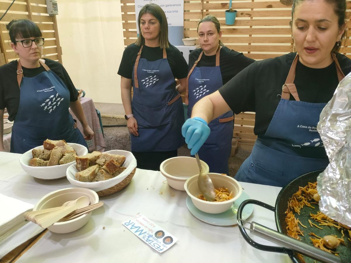 Unas cocineras sirven algunos de los platos.