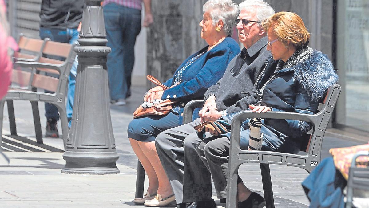 Varias personas mayores sentadas en un banco.